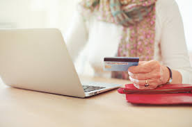 individual holding card while typing on laptop