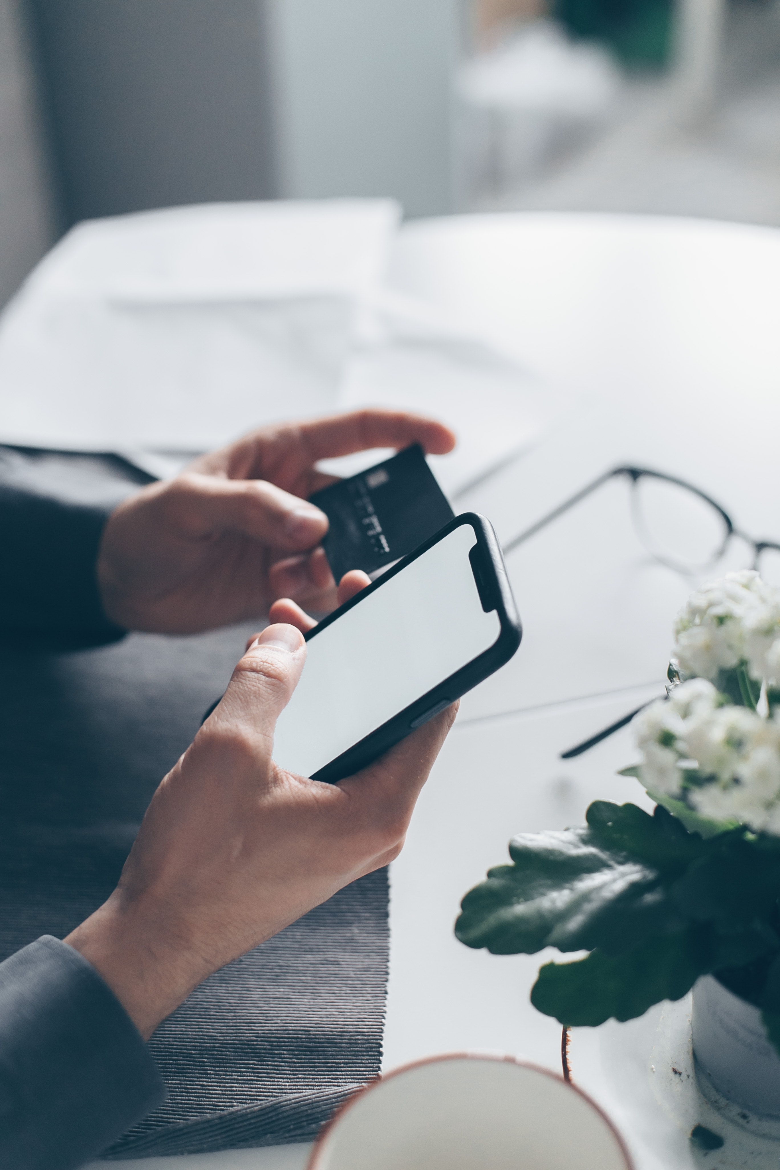 individual holding credit card in one hand and cell phone in the other