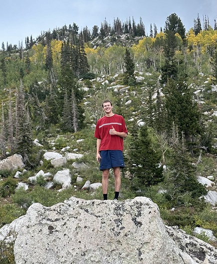 Tall student hiking in Utah with a thumbs up sign!