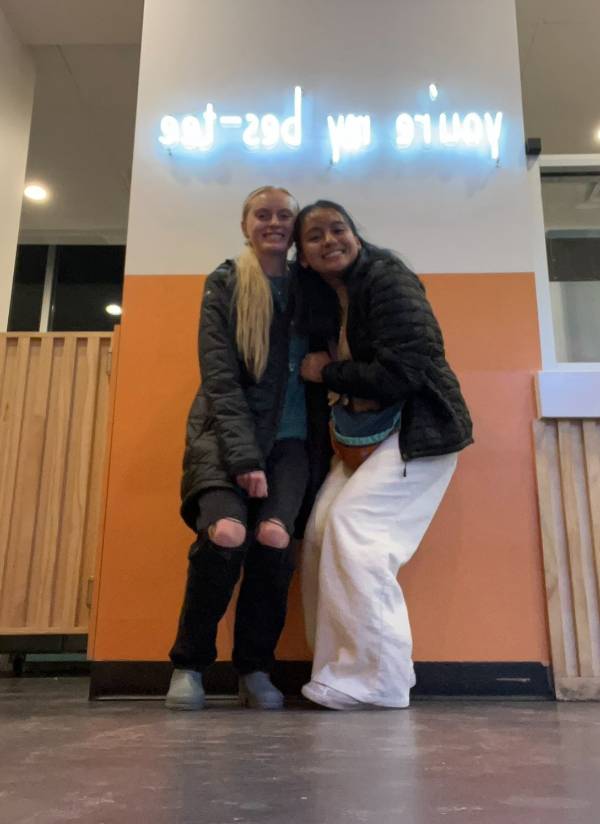 lucy and her friend smiling in front of a building column