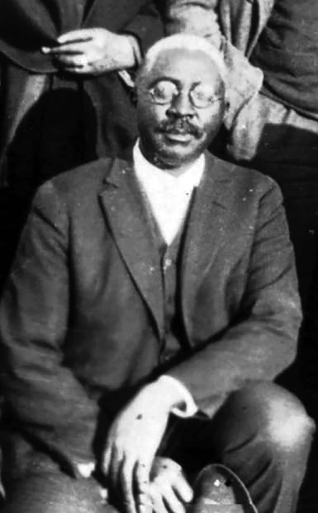 Historical photo of O.W kneeling in suit