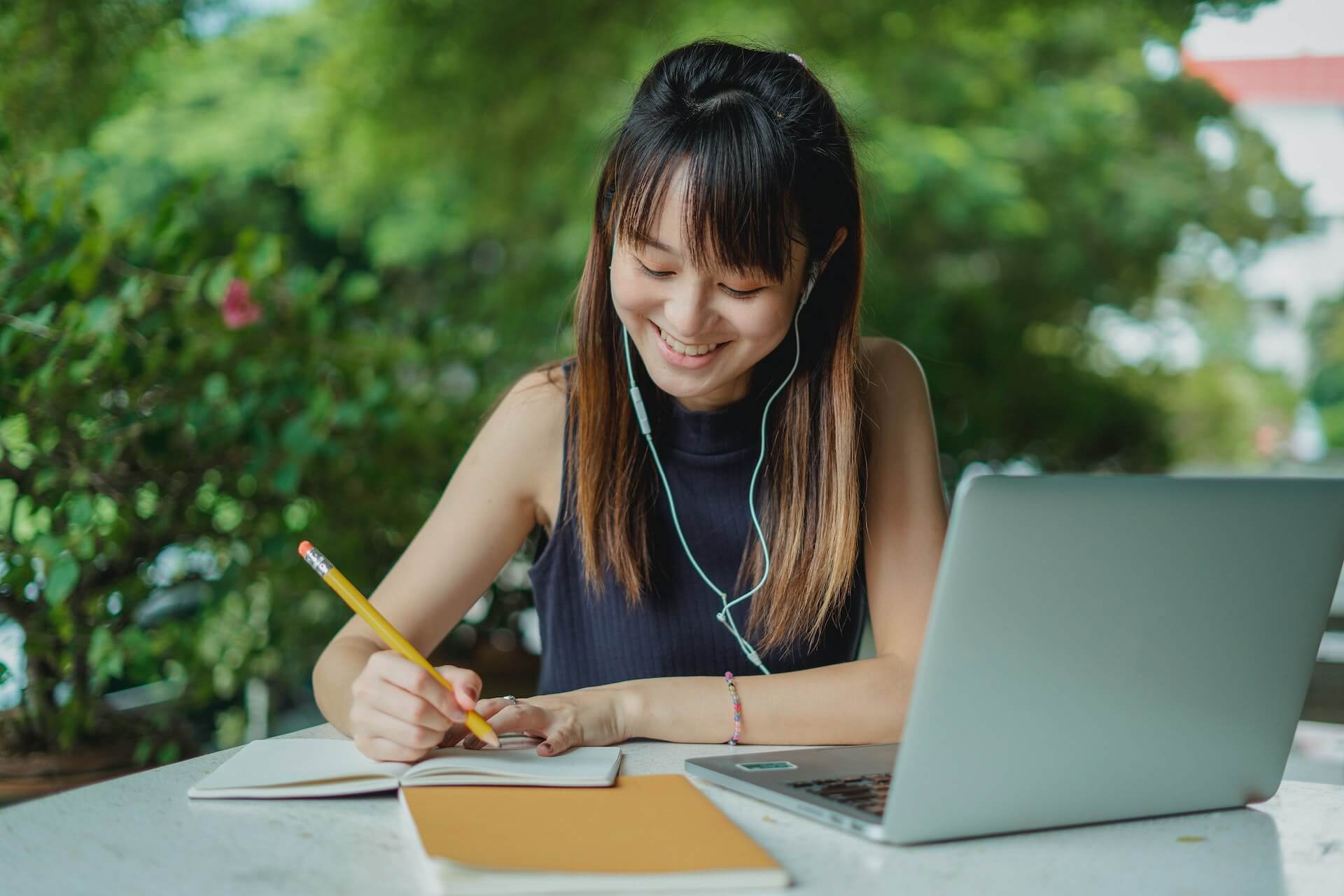 student writing scholarship essays on laptop with headphones in