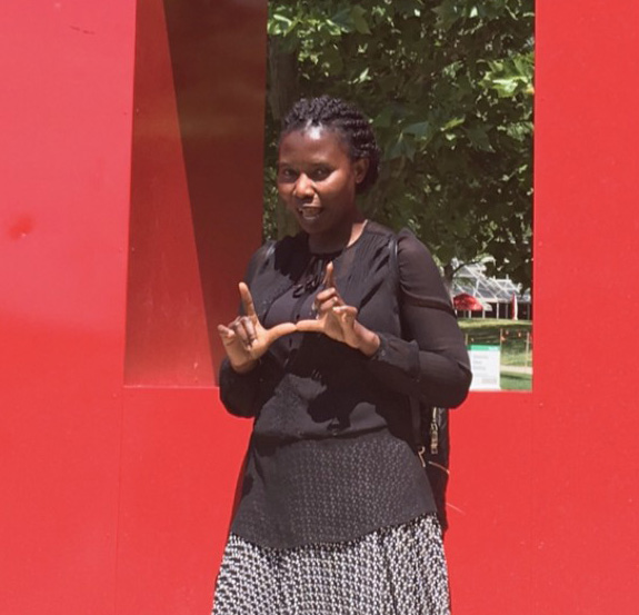 evelyn flashing the u with her fingers while standing in front of block u